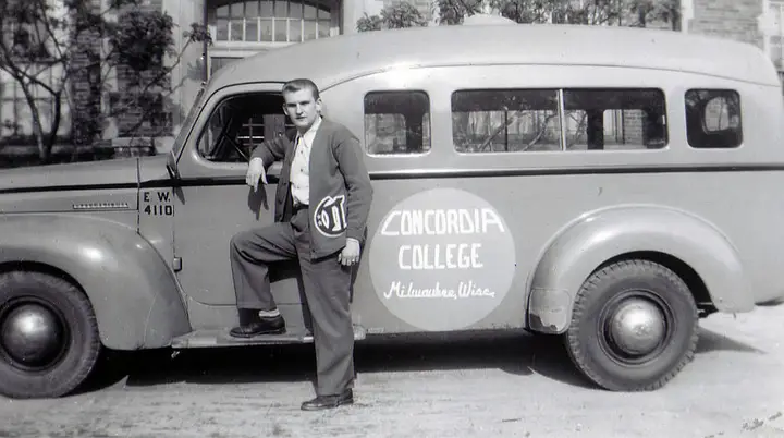 A man leaning on a 1940's style bus branded with 