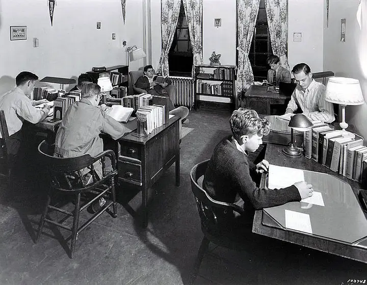 Group of young men reading and studying in a small room.
