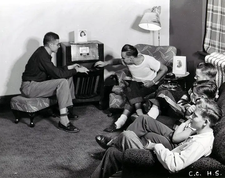 Group of young men sitting around a radio and relaxing.