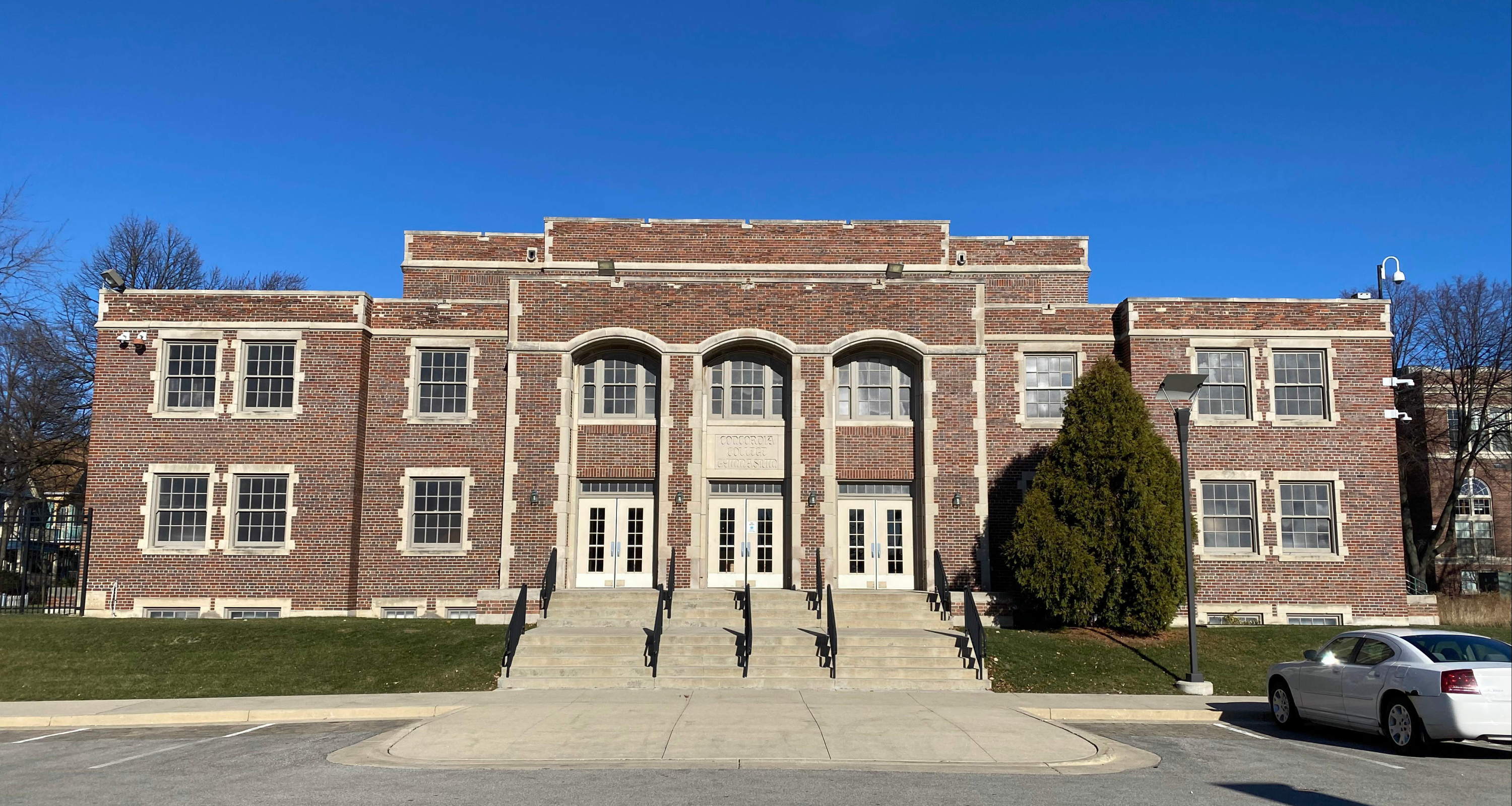 Two story brick gymnasium with "Concordia College Gymnasium" in limestone above the door.