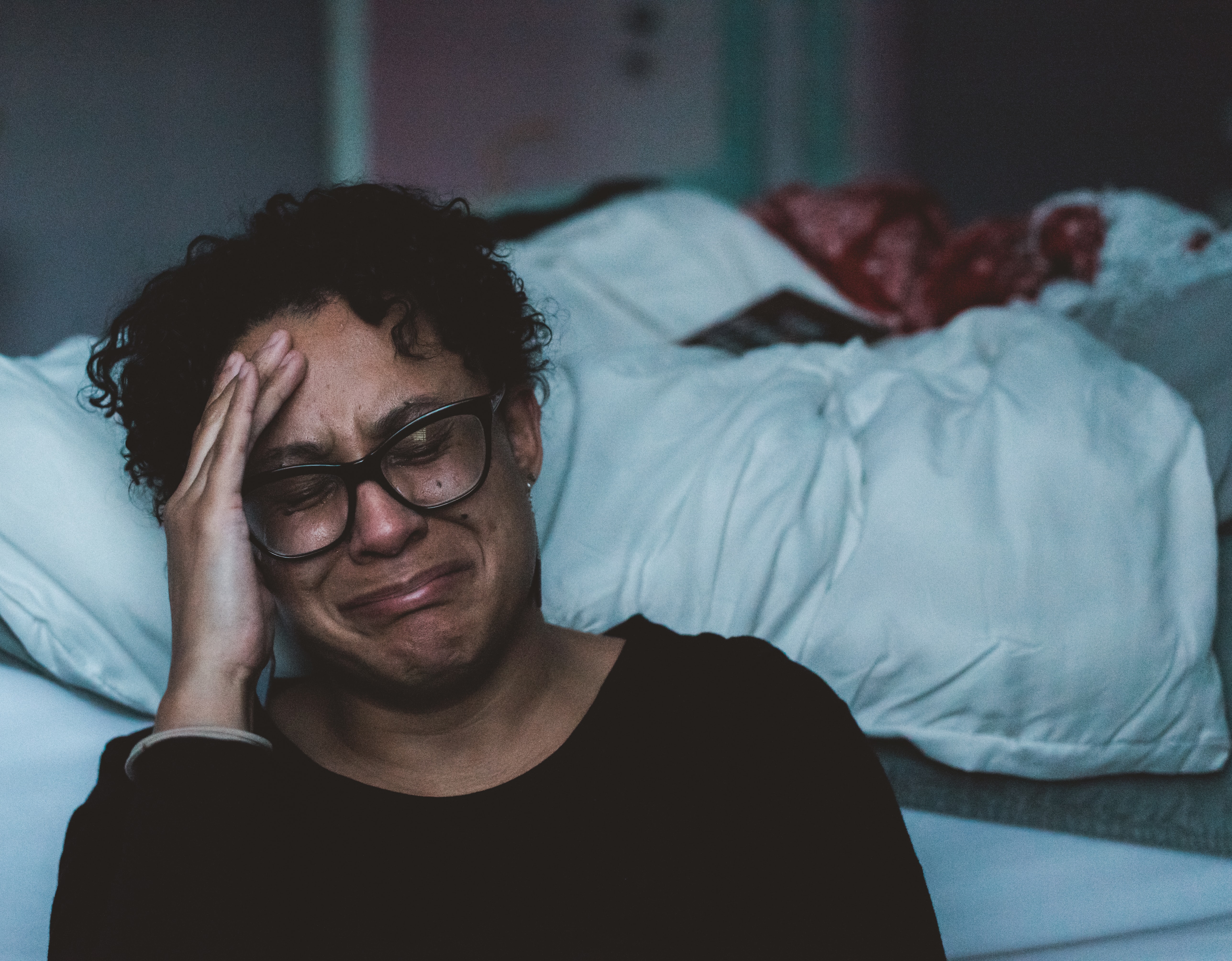 Woman sobbing beside a bed.