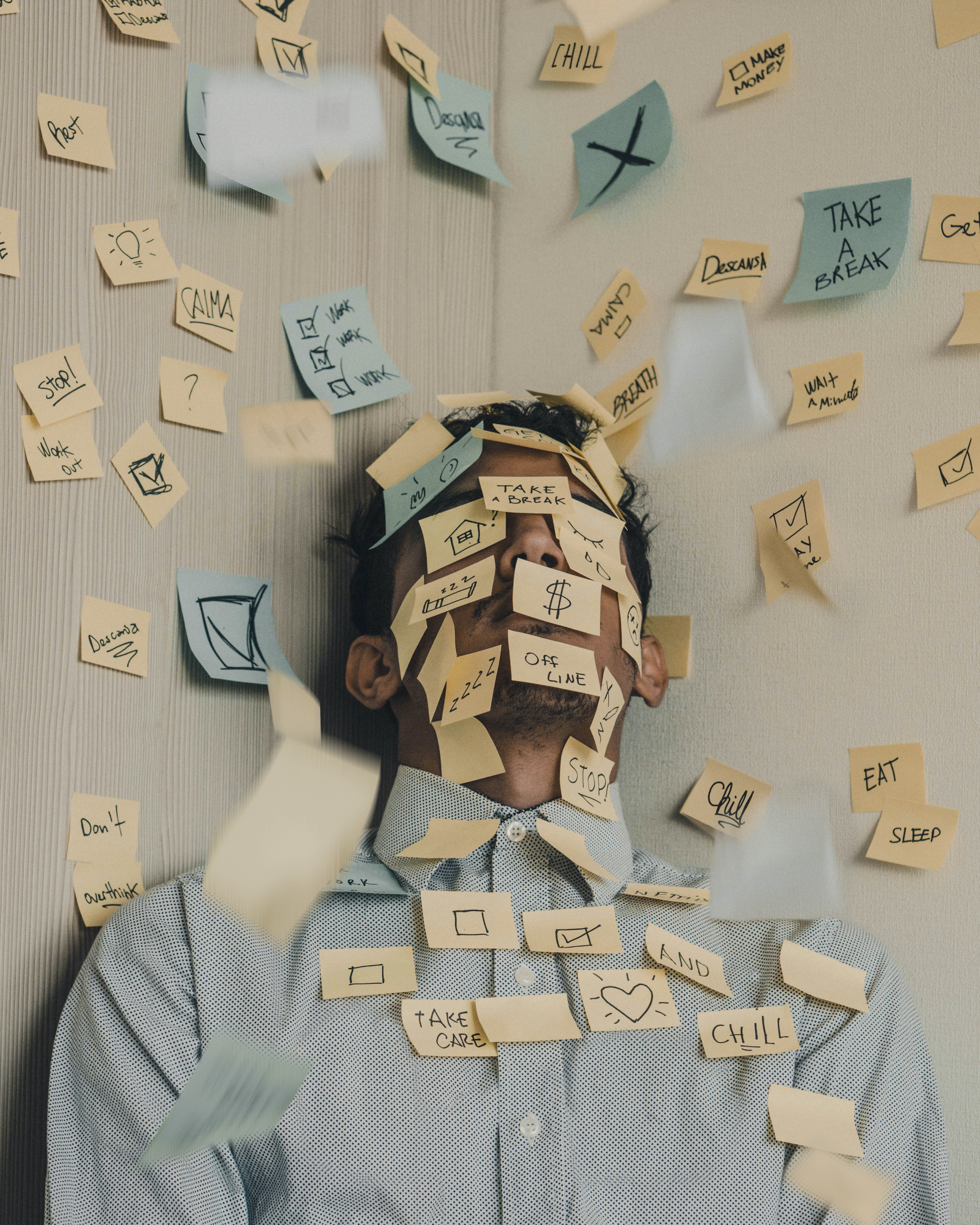 Man in the corner of a room covered in different post it reminders.