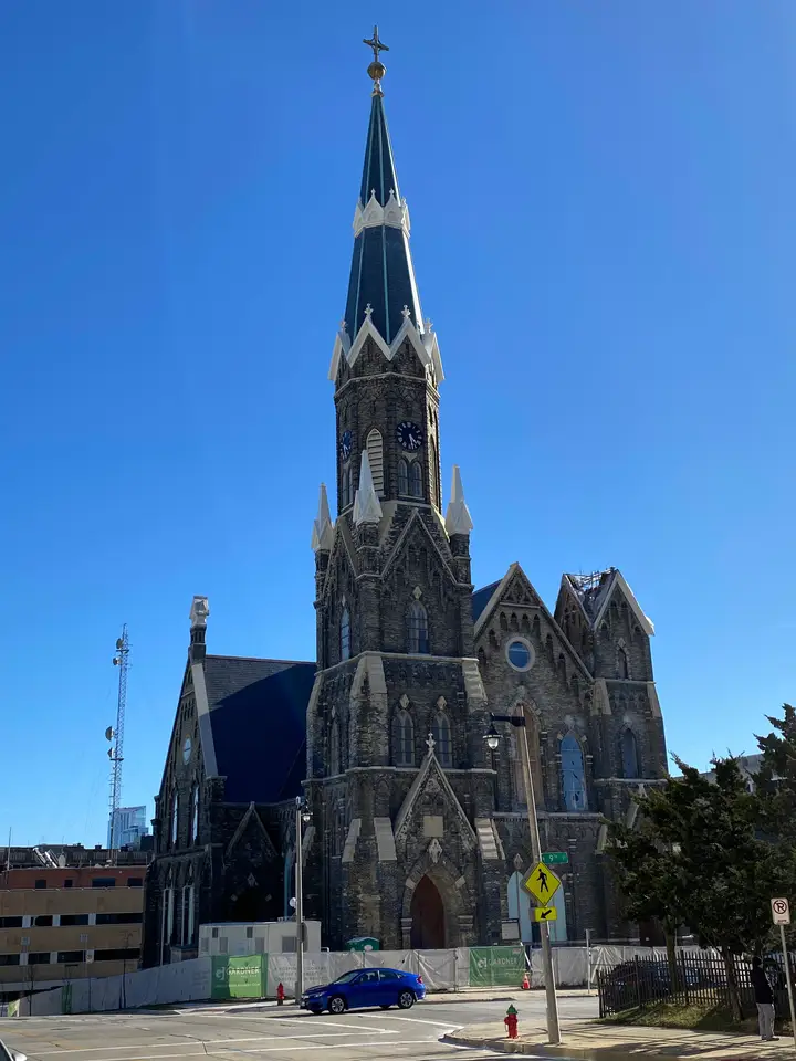 Trinity Lutheran Church; tall steeple in the front. Weathered, dark cream city brick covered church built on a street corner.