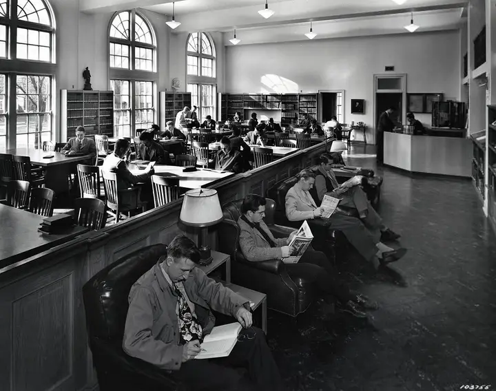 Facing the front windows there are several comfortable chairs with students reading in them. Behind them are the study tables.