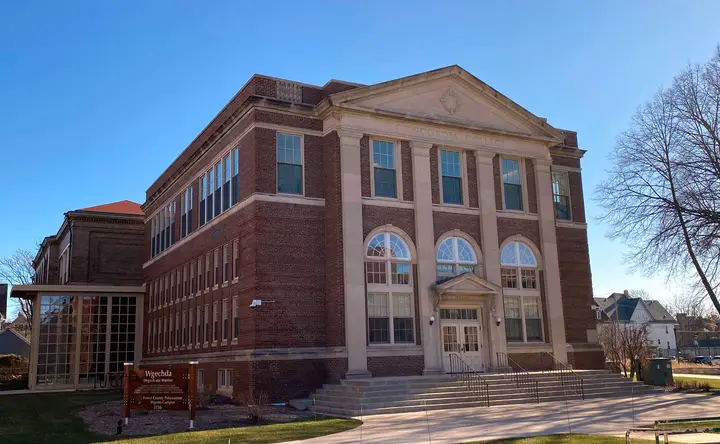 Front of the library from an angle presenting the one floor glass connector to a neighboring building.