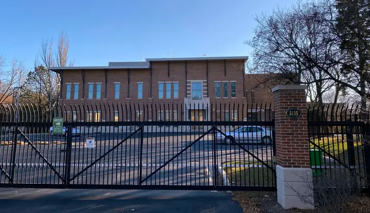 A new tall two story brick building with a large black fence protecting in front.