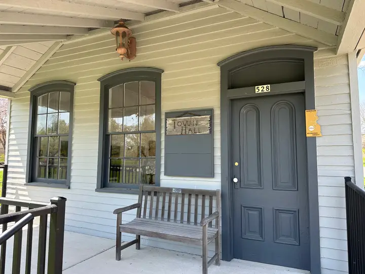 Town hall front porch with an old light fixture and a bench.